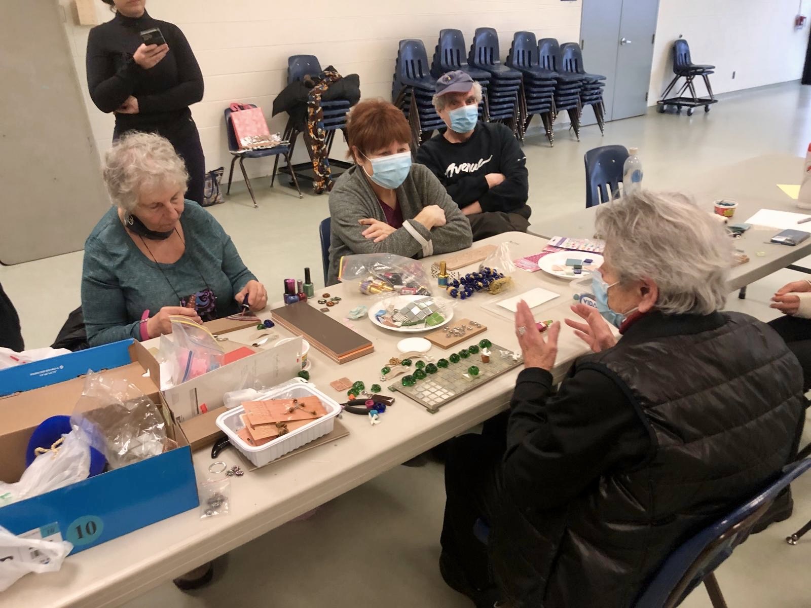 Older adults gathered around a craft table working on mosaic projects