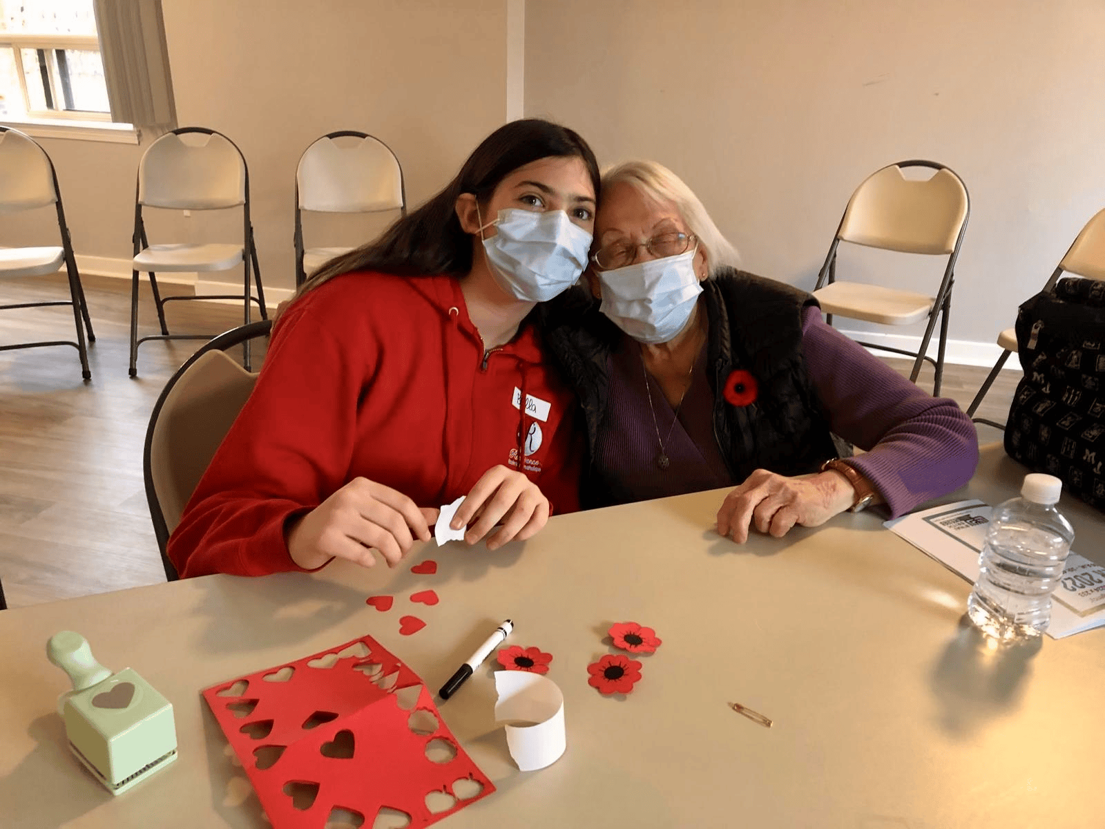 Facilitator and participant smiling together while crafting paper hearts